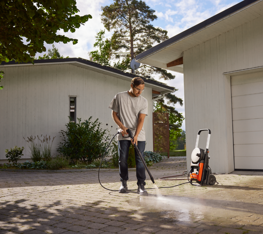 man cleaning driveway with pressure washer